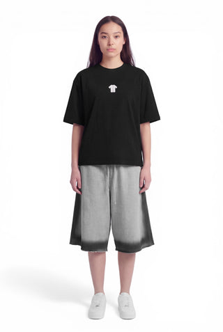 Person wearing a black t-shirt with a small white logo and gray shorts on a white background