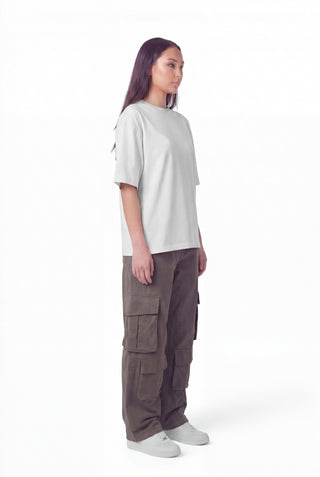 Person wearing a white oversized t-shirt and brown cargo pants on a white background