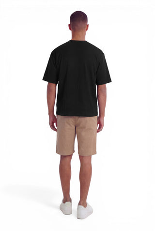 Man wearing a black t-shirt and beige shorts on a white background